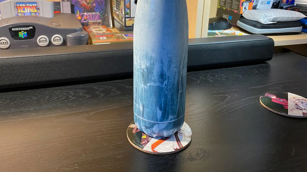 a tall water bottle on top of the coaster; coaster being used
