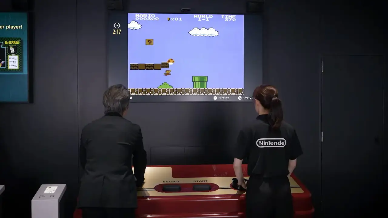 two people pressing buttons on a huge nintendo famicom controller