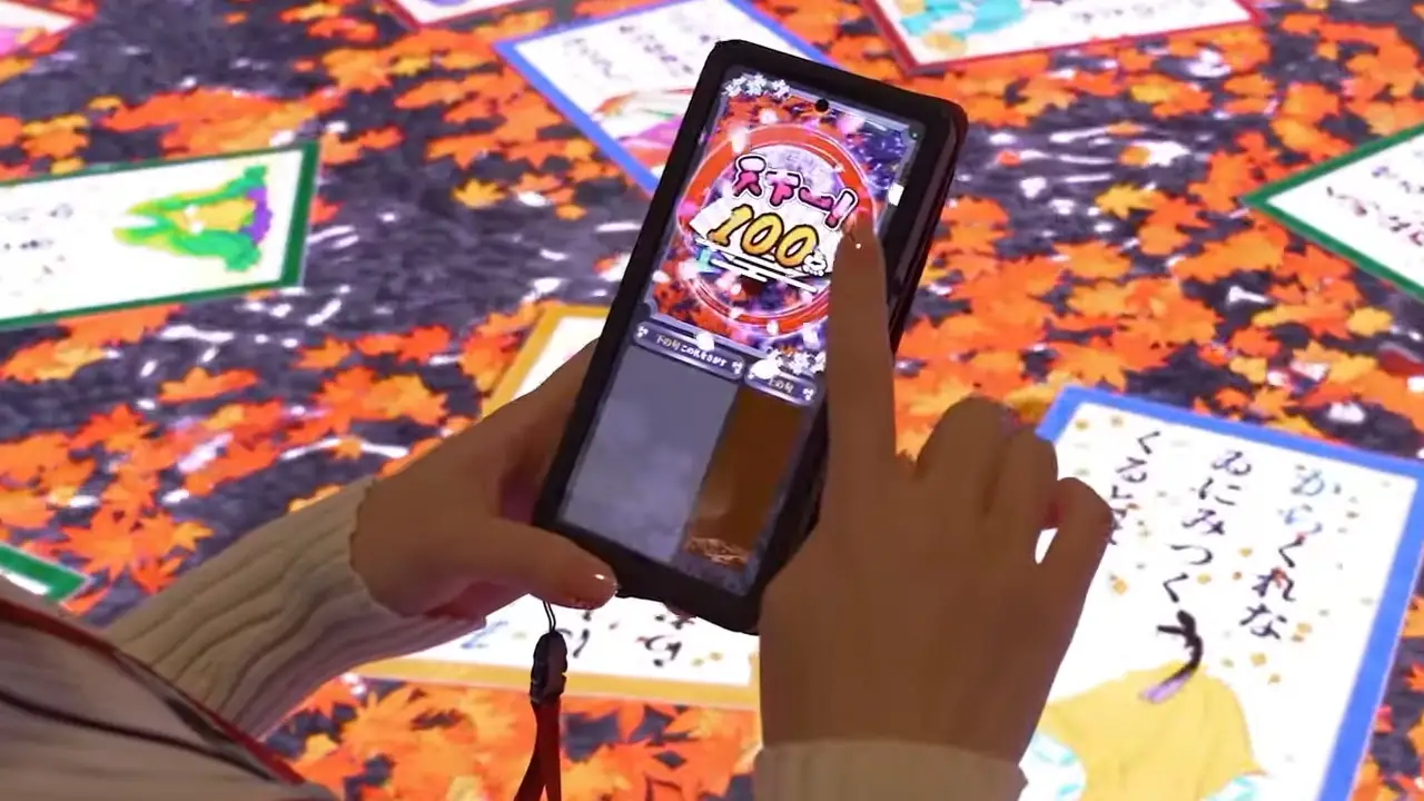 a hand holding a cell phone and playing a game on the floor screen below